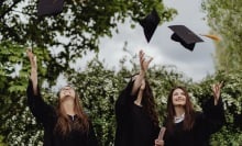 Three people throwing their graduation cap to the sky.