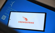 CrowdStrike logo on smartphone on top of Windows blue screen of death