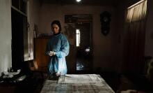 A woman in surgical dress stands alone in a room.