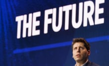 Sam Altman sits under a large screen that reads "The future."