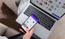 woman holding phone in front of laptop