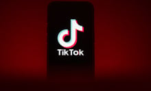 A phone in front of a red background showing the TikTok logo.