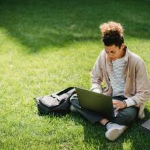 Student on lawn using laptop