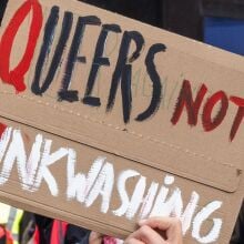 A pro-Palestinian protester from the Free Palestine Coalition holds up a sign criticizing Israeli 'pinkwashing' during a march through central London.