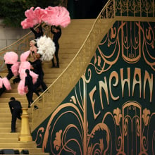 Lady Gaga and dancers stand on golden steps that read "Enchanté".