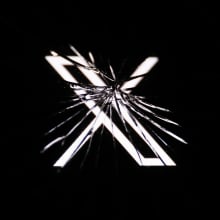 X logo behind broken glass