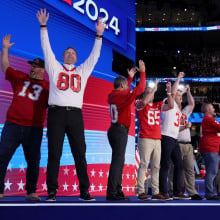 grown men in football jerseys on the DNC stage, all former players for Tim Walz