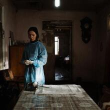 A woman in surgical dress stands alone in a room.