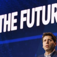 Sam Altman sits under a large screen that reads "The future."