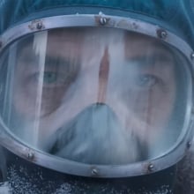 A close-up of a man in a radioactive suit standing outside in the snow.