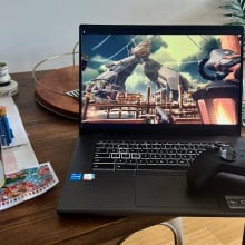 Acer Chromebook 516 GE gaming laptop on crowded desk next to indoor plant