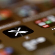 A blurry phone screen, with only the X app logo in focus. 