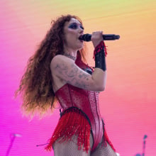 chappell roan onstage with a multicolor, bright background. 