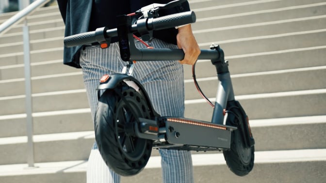 stylish man carrying folded hiboy s2 scooter up steps