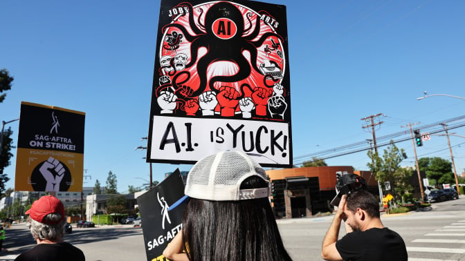 A union protestor holds up a sign that says "AI is yuck".