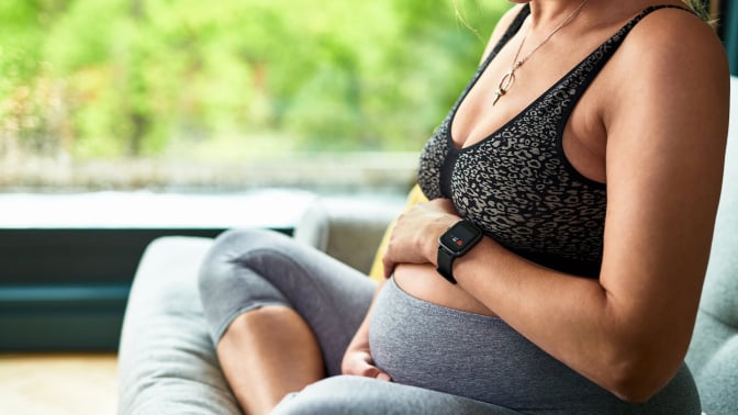 A pregnant woman sits with her legs crossed.