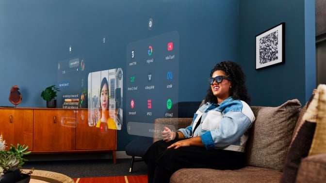 woman sitting out couch looking at apps wearing orion meta glasses