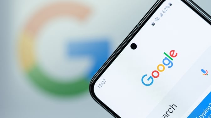 Google search app on smartphone screen close up with blurred logo background.