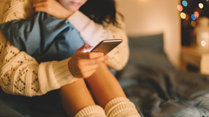 Girl looks at phone in a seated position. 