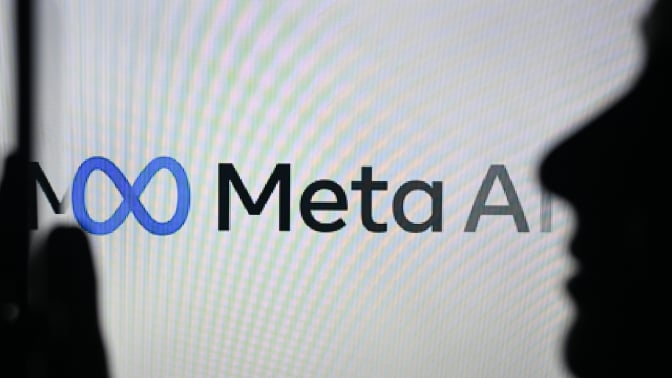 A person holding a cell phone in front of the Meta AI logo displayed on a computer screen, on April 29, 2024, in Edmonton, Canada.