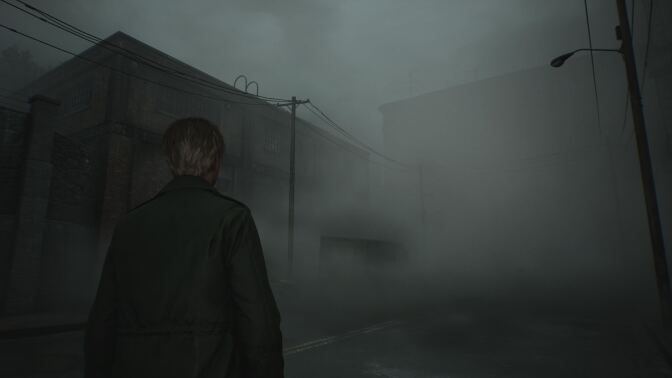 A person with short hair, wearing a dark coat, is standing on a foggy, deserted street. The atmosphere is eerie, with thick mist obscuring much of the surroundings, including power lines and dimly visible buildings in the background. The scene evokes a sense of isolation and tension