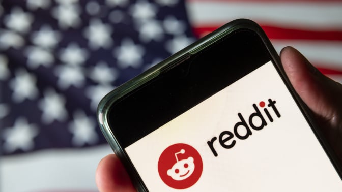 A phone displaying the Reddit logo in front of an American flag.