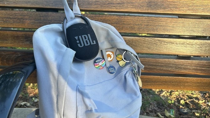 jbl clip 4 attached to a blue backpack on a bench