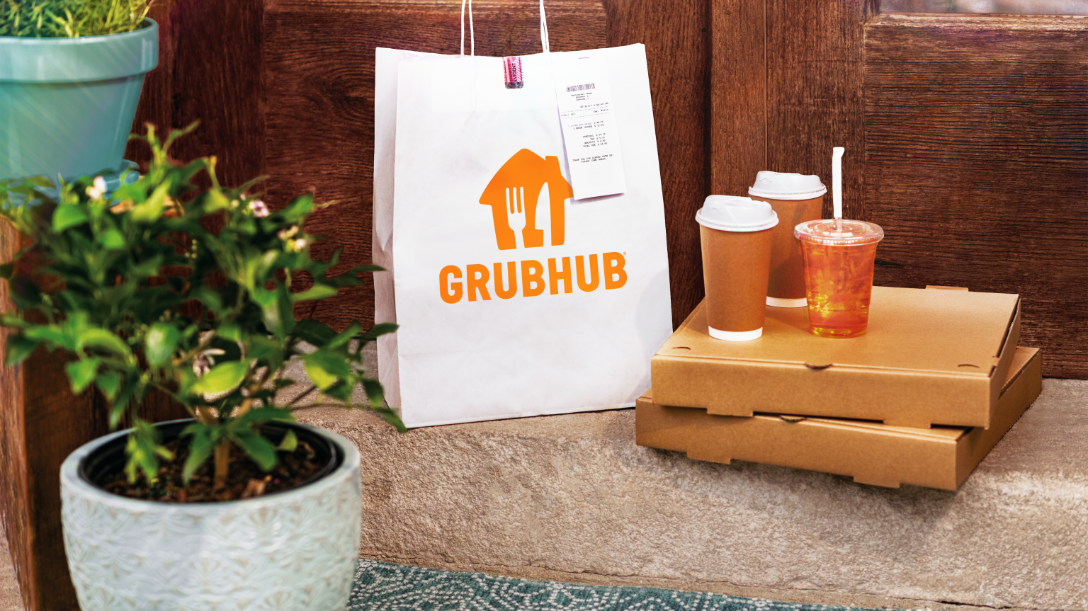 a grubhub bag on a bench with delivery boxes and drinks