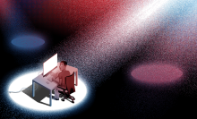 A spotlight shines on a man at his computer desk.