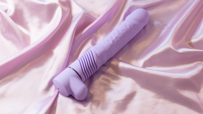 purple thrusting dildo lying on bed sheets