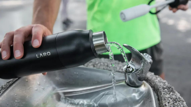 person filling up water bottle at drinking fountain