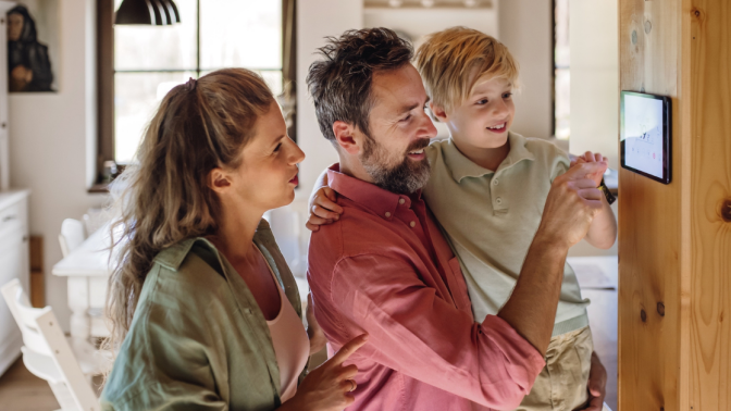 family of three looking at a smart thermostat