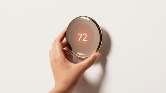 a close-up of a hand adjusting a google nest learning thermostat (4th gen)