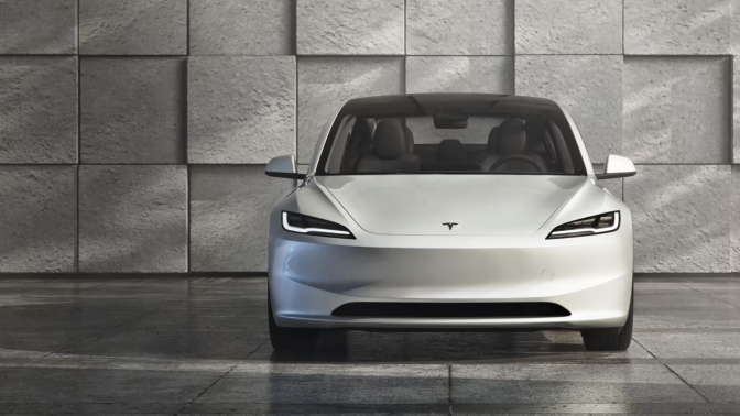 Tesla Model 3 sits in a modern, grey, concrete space.